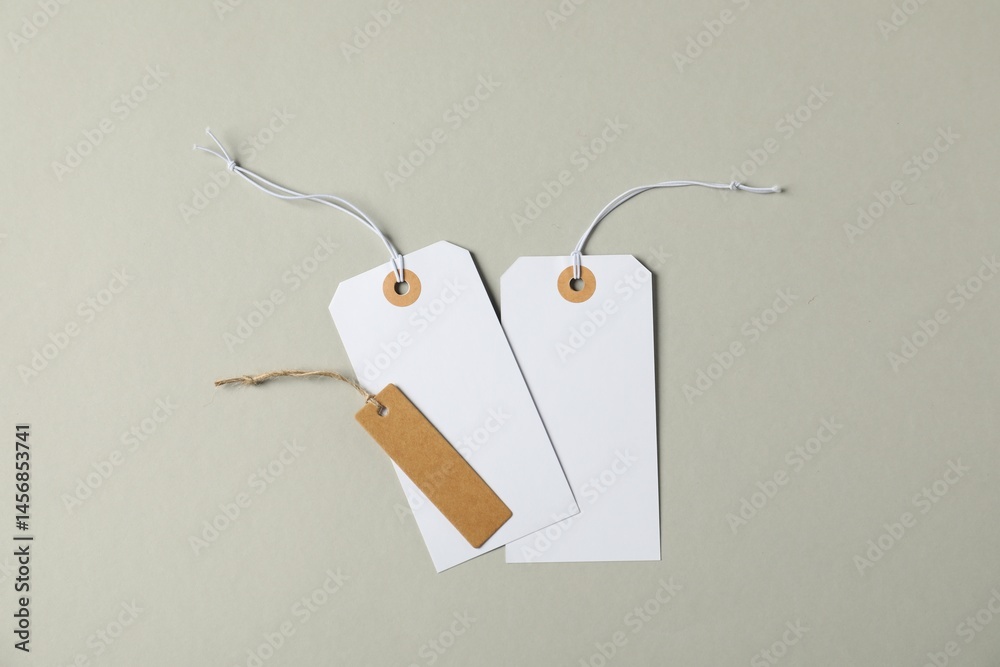 Naklejka premium Blank tags with strings on grey background, flat lay