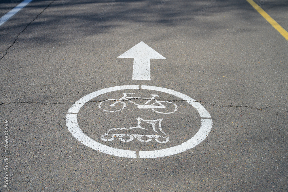 Fototapeta premium white sign for cyclists and rollerbladers on asphalt path in park