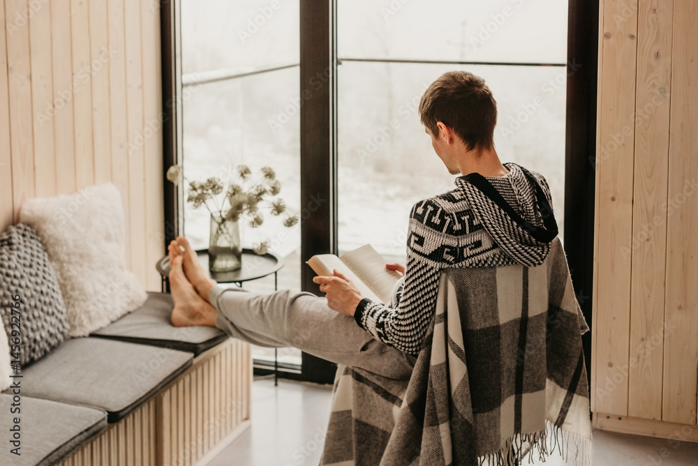 Man Reading Book in Log Cabin in Winter