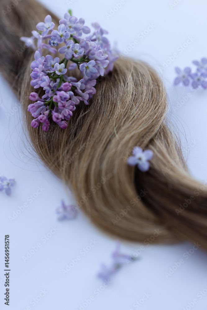 Naklejka premium Hair with lilac flowers. Closeup, selective focus.
