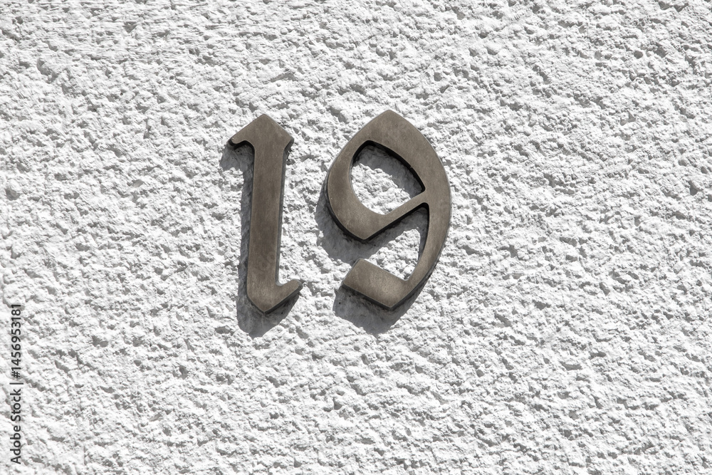 house numer 19 at a white wall