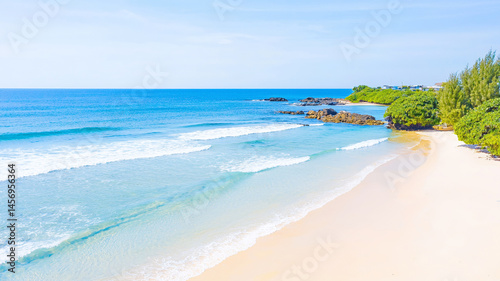 serene beach scene featuring gentle waves lapping at shore, surrounded by lush greenery and rocky formations