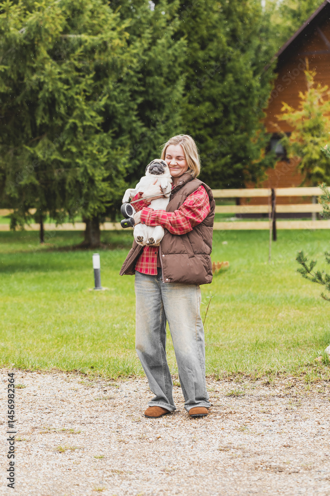 Fototapeta premium beautiful girl walking with a dog, girl holding a pug in her arms