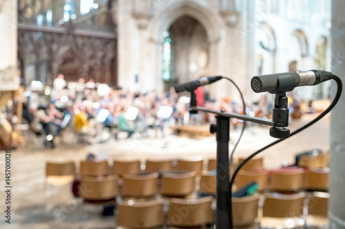 Obraz na płótnie Shallow focus of a professional singers microphone seen near a classical orchestra in rehearsal for a forthcoming public event. A large number of seats can be seen, which will be used by the public. w salonie