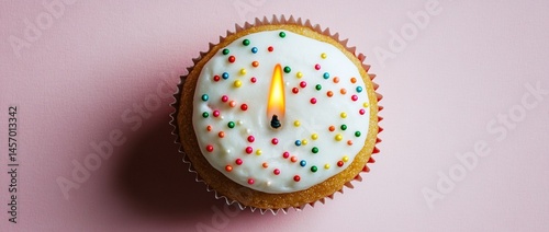 Obraz na płótnie Single cupcake with lit candle and sprinkles on pink background. w salonie