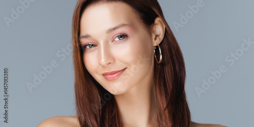 Caucasian woman with glossy brown hair, natural makeup, and radiant skin smiling softly in a clean studio portrait - ideal for beauty, skincare, wellness, or personal care brand promotions.