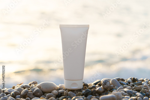 White mockup of a tube of cream on pebbles against the background of the sunlit sea. Concept of beauty products, natural face and body care, sunscreen