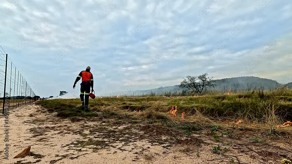 Firefighter manages wildfire along fence line of African wilderness park zone