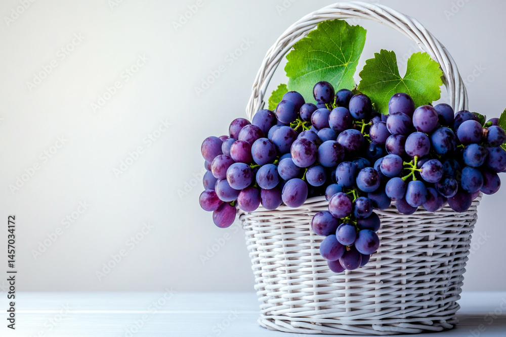 Freshly Harvested Purple Grapes in a Decorative Basket on a Light Surface Surrounded by Green Leaves