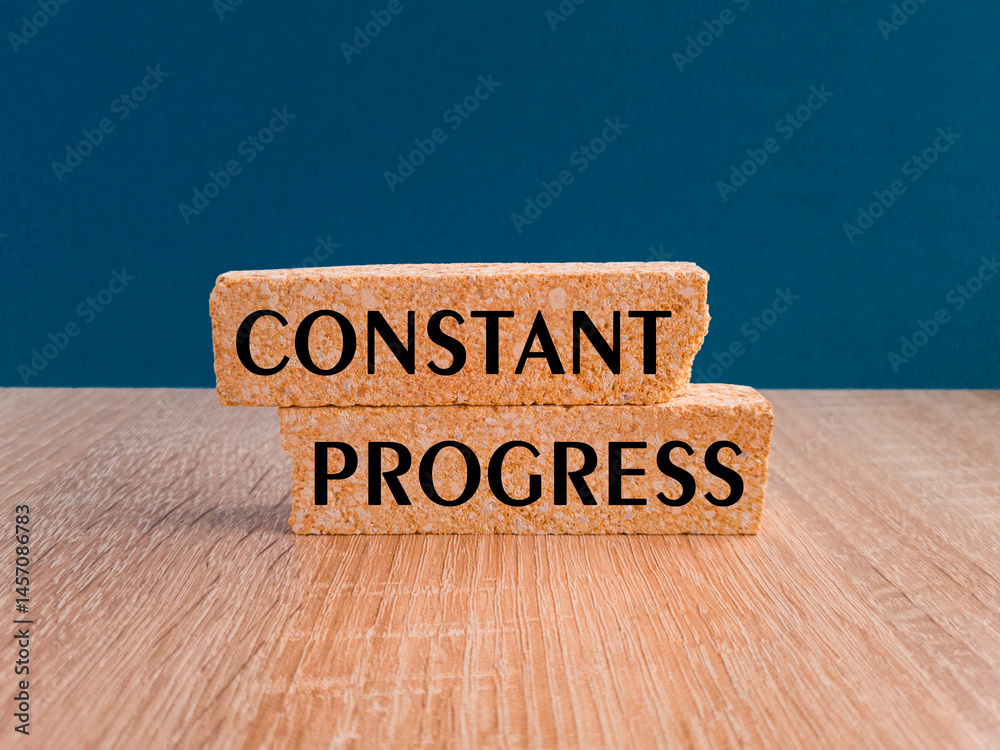 Brick blocks with words Constant Progress. Beautiful wooden table, dark blue background. Business concept.