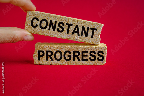 Obraz na płótnie Constant Progress symbol. Concept words Constant Progress on brick blocks. Businessman hand. Beautiful red background. Business and Constant Progress concept. w salonie