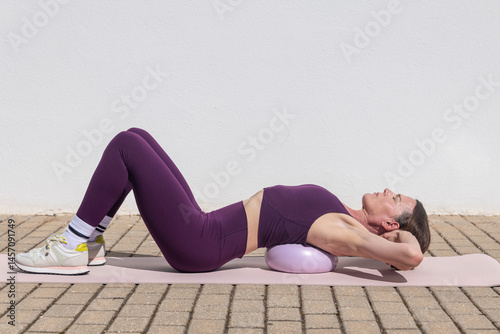 Fit woman doing pilates abdominal crunch exercise with a ball
