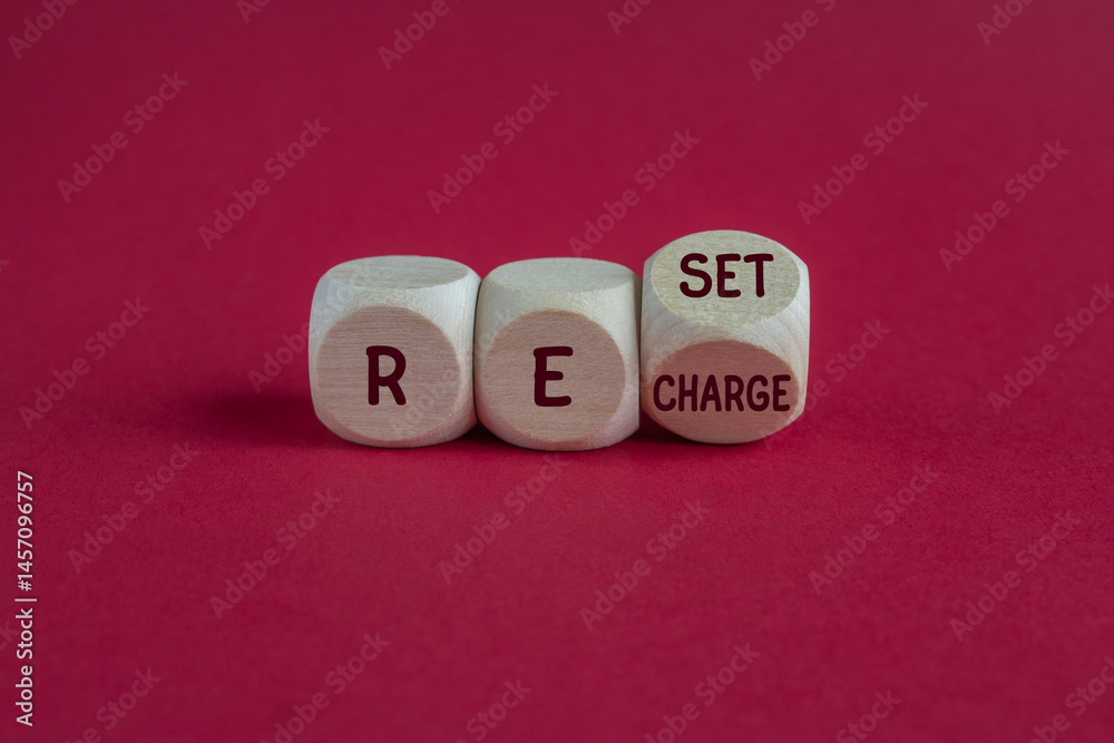 Wooden cubes form the expression Reset Recharge. Beautiful red background. Business reset and recharge concept.