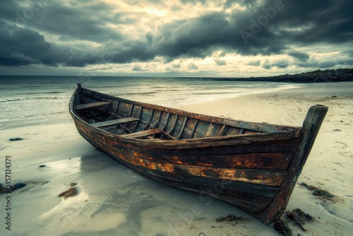 A weathered wooden rowboat on a sandy beach under a dramatic sky.  The boat is old and shows signs of age and exposure to the elements