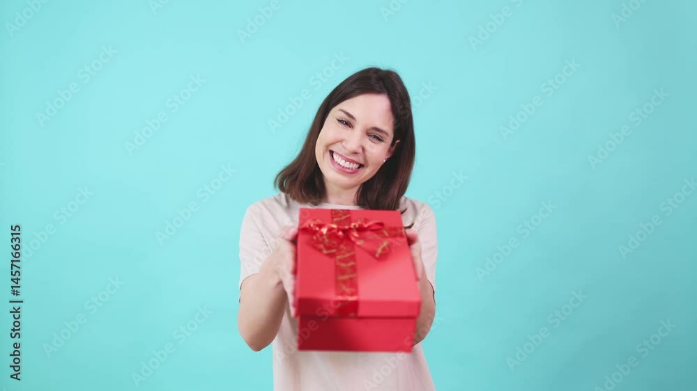 Woman offering red gift box on turquoise background Woman offering red gift box on turquoise background