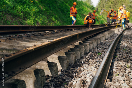 A worker in the process of arailroad track weld repair with a freight train passing