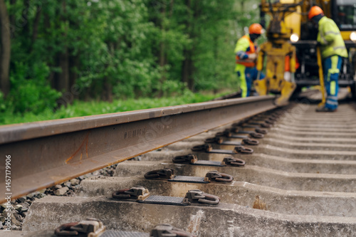 A worker in the process of arailroad track weld repair with a freight train passing