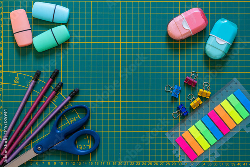 Colorful School Supplies on Cutting Mat. Bright stationery items arranged on a green cutting mat, perfect for school or office concepts.