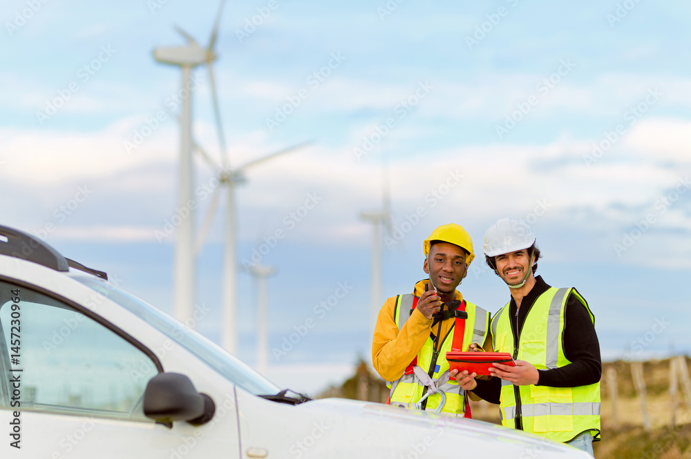 Two engineers in safety gear discuss operations at a wind farm, highlighting teamwork and renewable energy in a modern setting