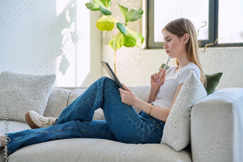 Obraz na płótnie Young woman using digital tablet sitting on sofa at home w salonie