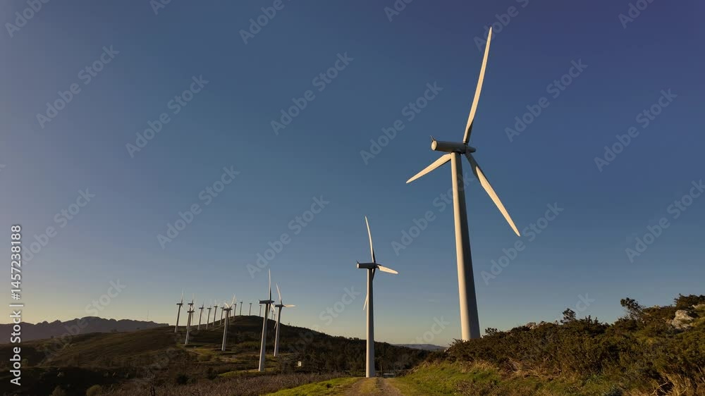 Wind turbines rotating under blue sky in wind farm Wind turbines rotating under blue sky in wind farm