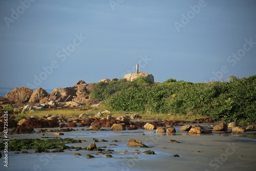 Rocks spread out on the beach sand, hill covered by green vegetation, sunny day light, clear sky. Wastern side of  Itacuruca beach, Cananeia, Sao Paulo state