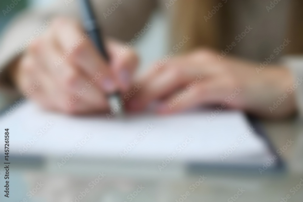 A Person Taking Study Notes in a Notebook, Focus on Hand and Pen, Blurred Background