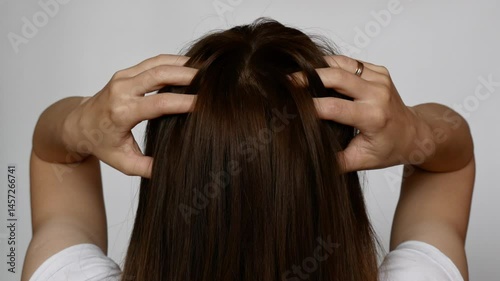 Woman scratching dry scalp with dandruff. Concept of itchy skin, hair problems, and scalp irritation.