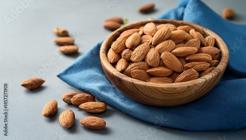 wooden bowl full of raw almonds sits on gray table with blue napkin creating warm and inviting scene promoting healthy eating and snacking