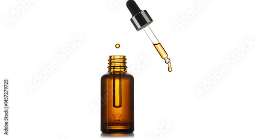A single, precise drop of golden-yellow liquid, likely a cosmetic serum, essential oil, or tincture, falls from a glass pipette towards the opening of an open amber glass dropper bottle below photo