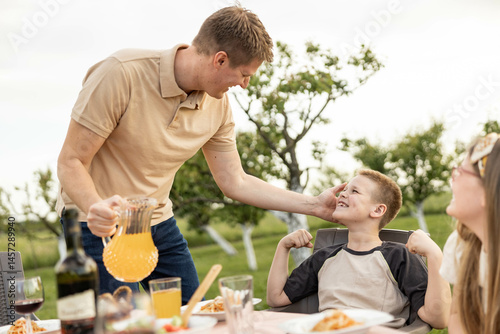 Foto A joyful family lunch outdoors featuring a father and son sharing a playful moment among friends with delicious food around