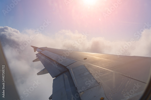 Soaring above the clouds at sunset while on a flight surrounded by vibrant hues of orange and pink