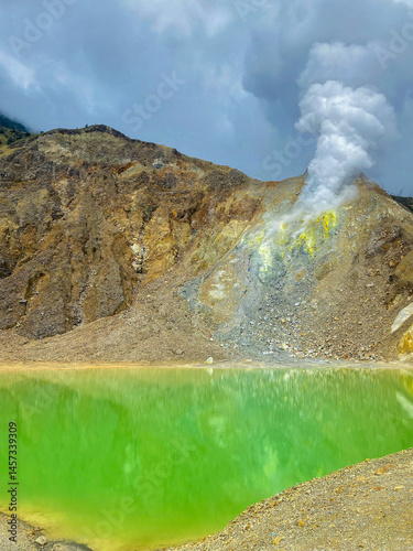 Landscape of fumarol with a yellowish green volcanic lake containing sulfur,Caldera.Fumarol emit thick steam gas,the yellow color in the fumarol area indicates the presence of sulfur content,Solfatara