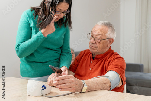 Daughter carefully checking her senior father's blood pressure at home, providing support and care for his health