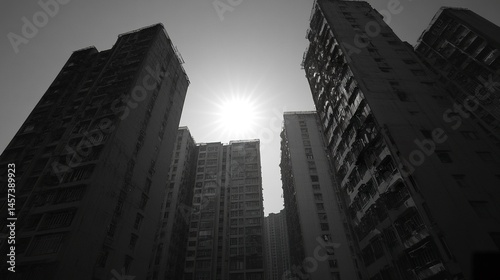 High-contrast black and white image of a sunlit building, towering among other tall structures, highlighting urban density and architectural sophistication.  