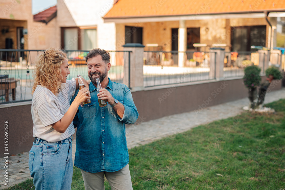 Fototapeta premium Couple drinking beer and enjoying backyard of house