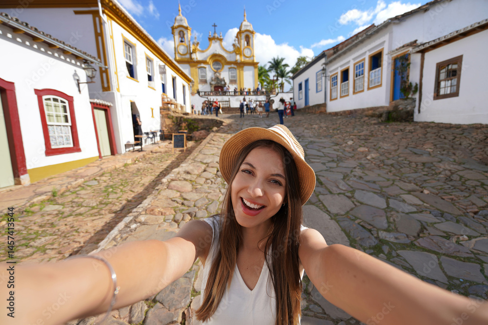 Tourist girl takes self portrait in the historic center of Tiradentes with on background the Mother Church of Saint Anthony, Tiradentes, Minas Gerais, Brazil