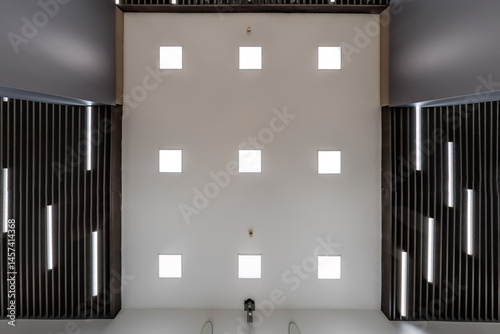 cassette suspended ceiling with square halogen spots lamps and drywall construction in empty room in apartment or house. Stretch ceiling white and complex shape. Looking up view