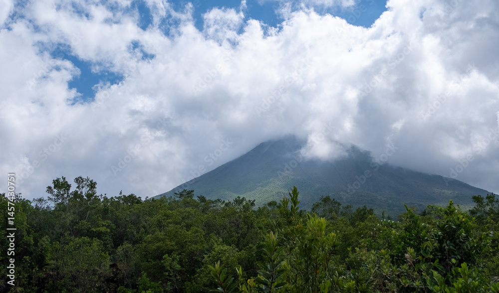Arenal volcano emerging from the forest under cloudy sky. Costa Rica national park