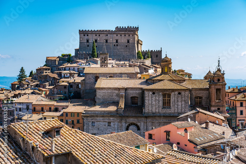 Scenic view of Soriano nel Cimino in Latium. Italy. Showcasing its historic medieval castle and charming rooftops under a clear blue sky. The town's layered architecture highlights its rich heritage