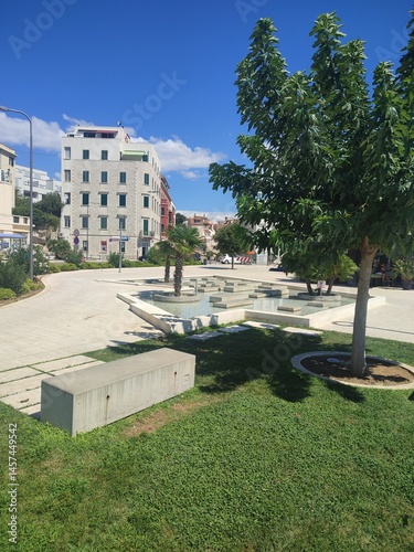 Modern Urban Park with Trees, Benches and Historical Architecture in Background