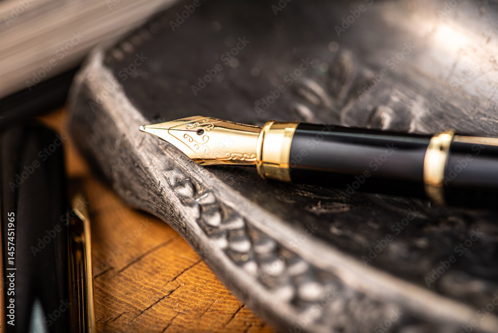 Naklejka premium Fountain pen, a beautiful fountain pen with books and other objects on a rustic wooden surface, selective focus.