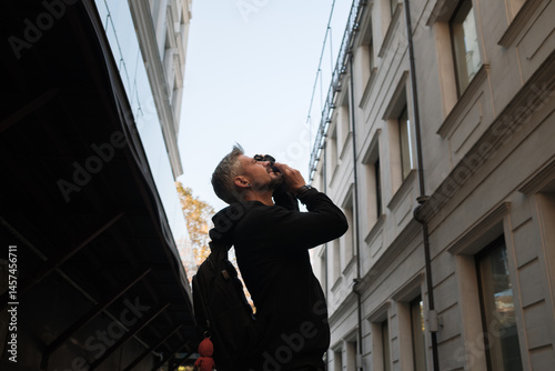 A person gazing upwards beside urban buildings, evoking curiosity and exploration.