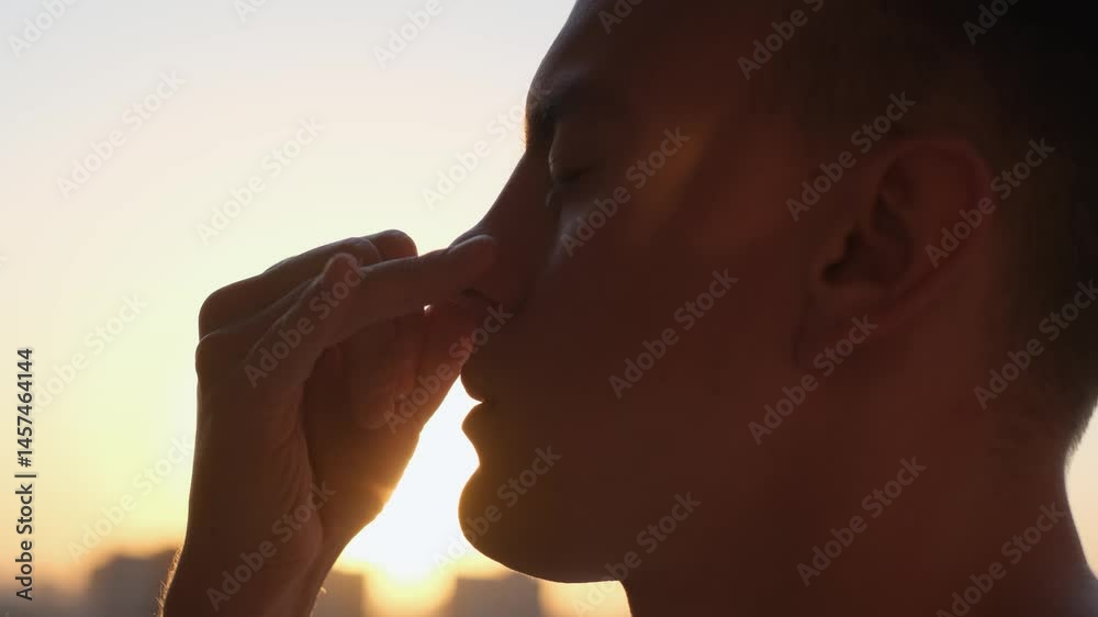 Man practicing controlled breathing technique at sunset. Pranayama and yoga concept