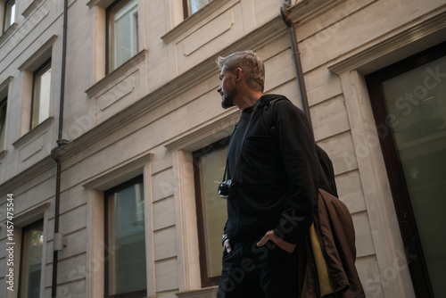 Wallpaper Mural A man walking outdoors in an urban setting, carrying a camera and wearing black Torontodigital.ca