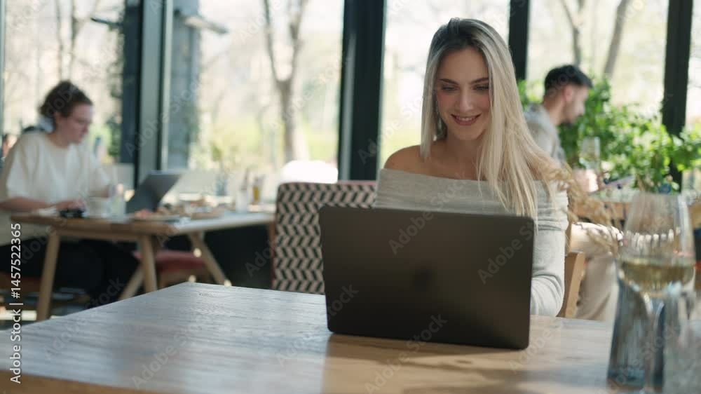 Young freelancer woman working on laptop in cafe