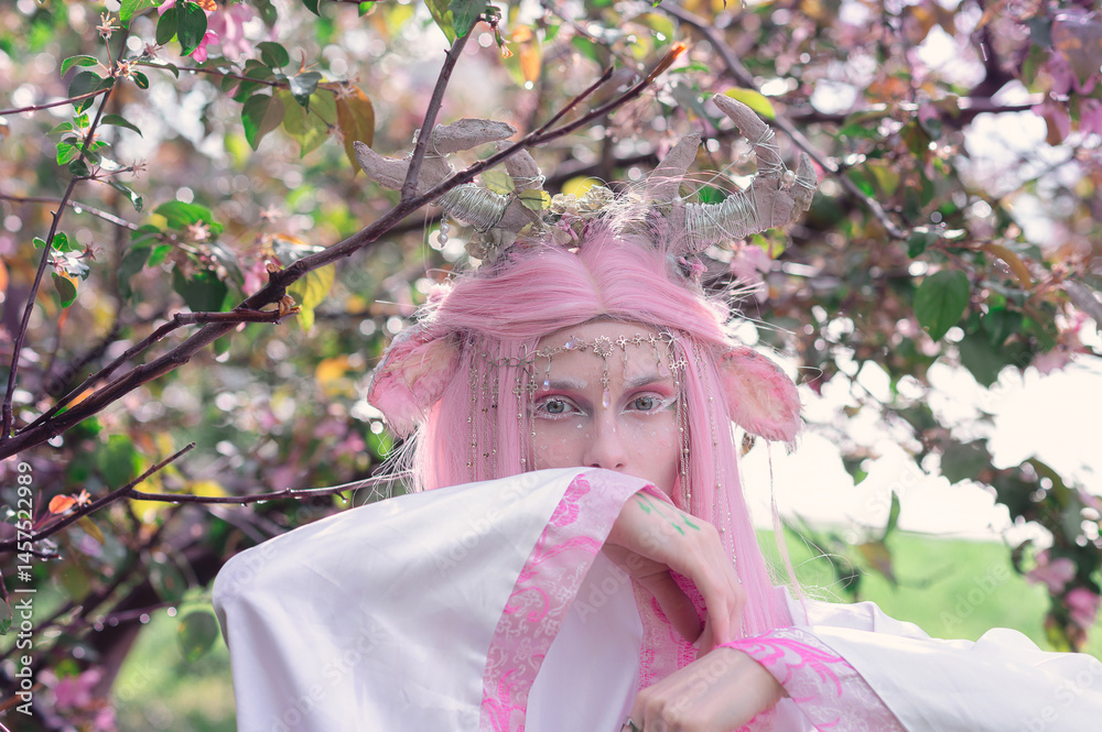 Deer dryad girl against the background of a blooming pink apple tree