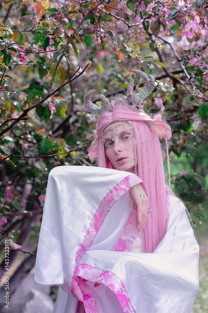 Deer dryad girl against the background of a blooming pink apple tree