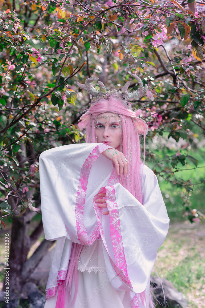 Deer dryad girl against the background of a blooming pink apple tree