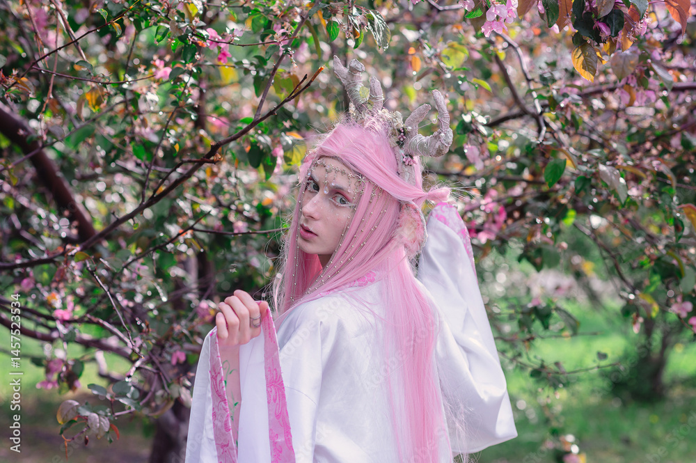 Deer dryad girl against the background of a blooming pink apple tree